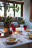 Gedeckter Tisch mit bunten Gläsern und Stechpalme in Kilndown cottage Kent England UK