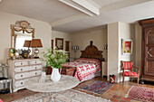 Patterned red quilt cover with chest of drawers and cut flowers in Suffolk home  England  UK