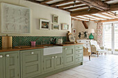 Belfast sink in light green fitted Suffolk farmhouse kitchen  England  UK