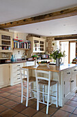 Bar stools at kitchen island in 18th century Norfolk barn conversion  England  UK