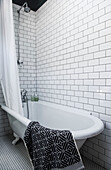 Freestanding bath in white tiled room with geometric bathmat in Whitstable home   Kent  England  UK