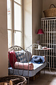 Antique decorative ironwork daybed beneath the tall window  gingham checked fabric cushions