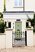 Cream facade of Amberley home with wrought iron gate and gateposts West Sussex England UK