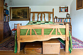 Geschnitztes Doppelbett und Bücherregale mit Aufbewahrungsboxen in einem Cottage in Devon, England UK