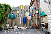 Collection of buoys hang from wooden fence in West Wittering West Sussex England