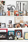 Fotografien und Ornamente auf weißen Regalen im Haus einer Londoner Familie, England, UK