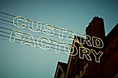 Großer Schriftzug 'CUSTARD FACTORY' in Neonlicht vor einem Wohnhaus in Birmingham UK