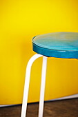 Turquoise leather stool set against yellow wall in Birmingham home  England  UK