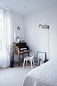 Wooden desk and chair in corner of white bedroom in contemporary London home   England   UK