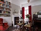 Polierter Esstisch und Bücherregale mit roten Samtvorhängen und Sessel in einem modernen Londoner Haus England UK