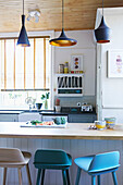 Assorted pendant lights above breakfast bar in kitchen of London family home  England  UK