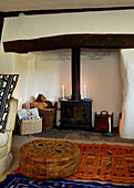Brown leather footstool at candlelit fireplace with wood burning stove in Brabourne farmhouse,  Kent,  UK