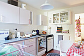 Kettle on hob with glass fronted kitchen cabinets in Faversham home,  Kent,  UK