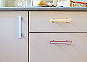 Retro style handles on cupboard drawers in Faversham kitchen,  Kent,  UK