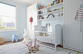 White crib below recessed shelving at window in London townhouse  England  UK