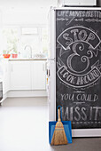 Dustpan and brush lean against chalkboard on side of fridge in Alloa kitchen  Scotland  UK