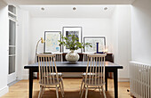 Leaf arrangement on table with white dining chairs in London home  UK