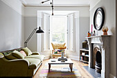 Runder Spiegel über einem Marmorkamin mit Vintage-Sofa in einem Londoner Haus UK