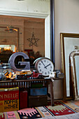 Buchstabe 'G' und Uhr mit einer Sammlung von Vintage-Ornamenten und einem großen Spiegel im Flur eines Hauses in Rochester, Kent, Großbritannien