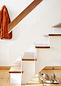 Orange coat and gold shoes in wooden staircase of London home  UK