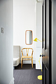 Gelbe Stehlampe mit Stuhl unter dem Spiegel im Gästezimmer eines modernisierten Hauses in Preston, Lancashire, England, UK