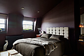 Pelzdecke auf Doppelbett in lilafarbenem Dachzimmer in einem Stadthaus im Osten Londons England UK