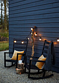 Pair of rocking chairs with  lit lights at woodclad exterior of Devon new build UK