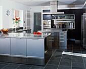 Modern fitted kitchen with frosted glass and stainless steel units with slate floor tiles