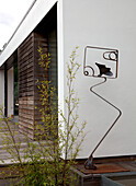 Metallskulptur und Pflanze vor modernem Anbau eines Hauses in Essex UK