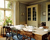 Wallpapered dining room with window display and painted cupboards