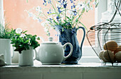 Display of crockery and kitchen utensils with herbs and flowers