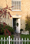 View of open front door through gate with front garden showing lawn and trees in berry