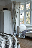 Pelzdecke auf dem Bett in einem Zimmer mit Zweigarrangement und gestrichenem Kleiderschrank