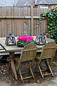 Umzäunter Tisch und Stühle mit rosa Blumen und Laternen