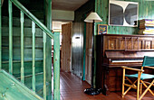 Staircase and boarded walls painted vibrant green wood stain in hallway with piano