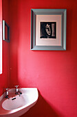Corner washbasin in vibrant pink cloakroom with modern artwork