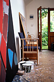 Farbdosen und Leinwand mit Stuhl in einem Künstleratelier in Suffolk mit offener Tür