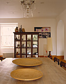 Old Indian tea cupboard in dining room with table made from reclaimed joists and uncurtained window 