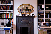 Ovaler Spiegel über Kamin mit Bücherregalen und Ablage