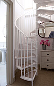 Spiral staircase with a chest of drawers and mirror 