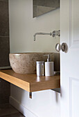 Stone bathroom sink on wooden counter in modern bathroom