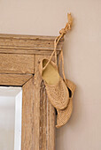 Traditional string shoes hanging on antique mirror frame close-up