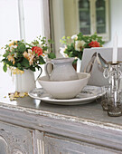 Flowers by crockery on cupboard