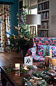 Weihnachtsbaum und Tisch mit brennenden Kerzen und Grünzeug im Landhaus in Hereford