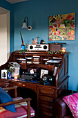 Schreibtisch mit blauer Wand und floralem Kunstwerk