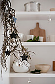 Star shapes hang in twig arrangement with homeware on shelves