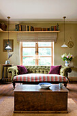 Shelf above window of Devon home with Chesterfield and wooden storage box