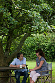Male and Female sitting in a garden drinking tea