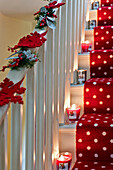 Lit candles and Christmas decorations on carpeted staircase of London home UK