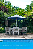 Poolside table and chairs with parasol in grounds of Canterbury home England UK